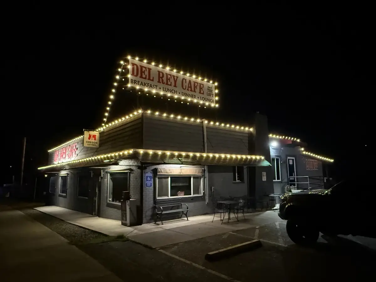The same cafe outlined in warm white holiday lights along the sign and rooflines
